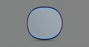 A tall, freestanding oval mirror unit measuring approximately 7 feet high and 3 feet wide, with a flawless, reflective surface. The mirror is framed in polished black onyx, matte in finish, with no visible seams. Two concentric LED-style rings encircle the mirror: the outer ring is electric blue and positioned just inside the frame, while the inner ring is violet and approximately 60% the diameter of the mirror. Between these rings, faint luminous markings and symbols suggest encoded information, softly pulsing. The top center of the unit houses a subtle projection module — a small inset lens that emits a faint vertical glow upward. The background is evenly lit in neutral gray to highlight the mirror without shadow. No human figure is present. The mirror stands in isolation as a sacred tech object.