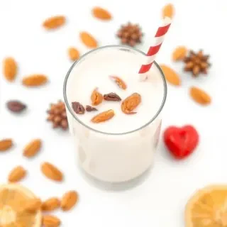 Almond milk with dried fruits, in a clear glass on a white background