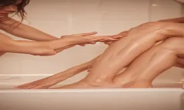 close up of mans hand on a woman's leg in the bathtub