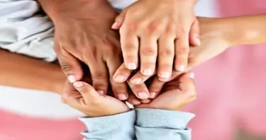 [Image: A family’s hands stacked together]